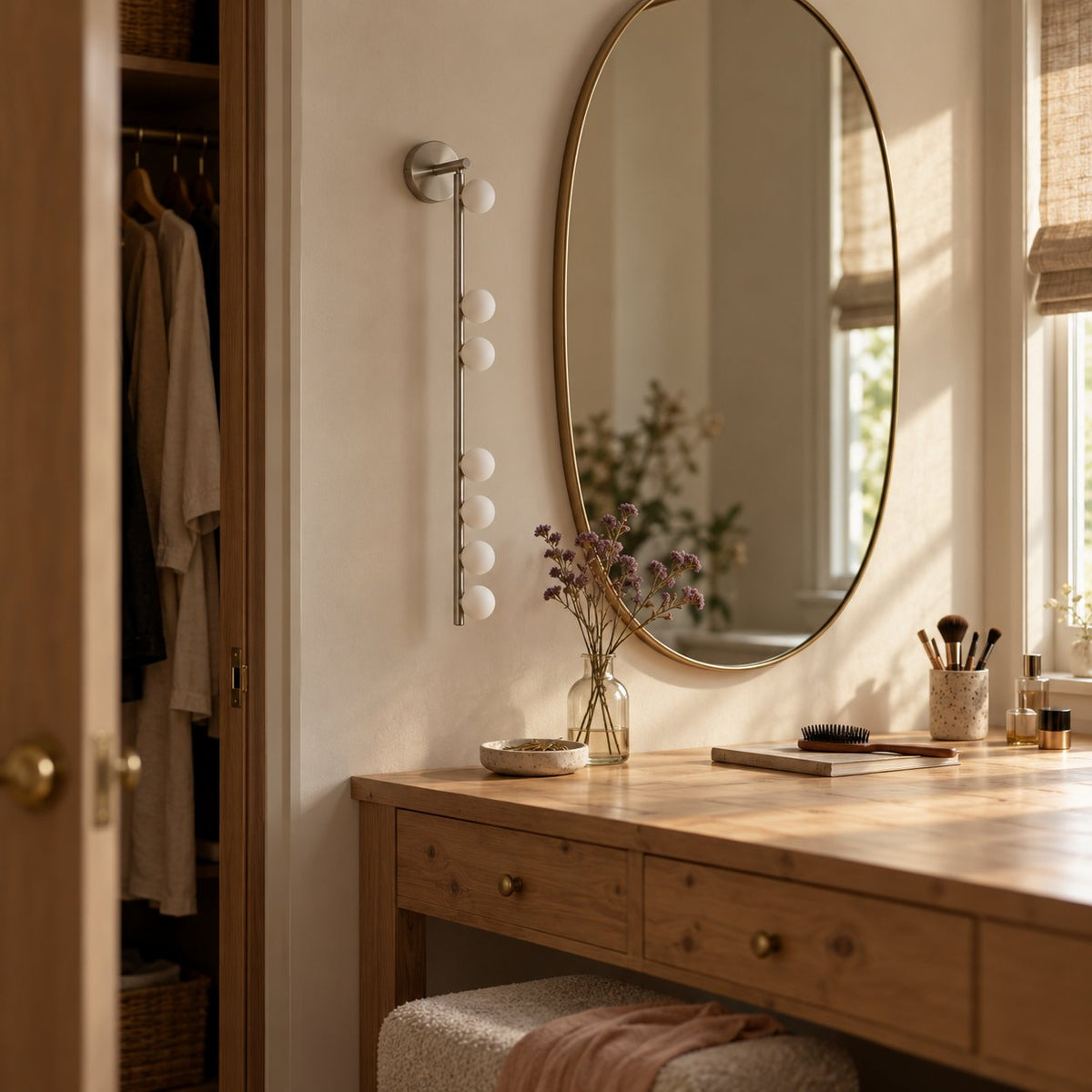 Vouga vertical bar wall sconce with small white glass globes in brushed nickel beside a mirror.