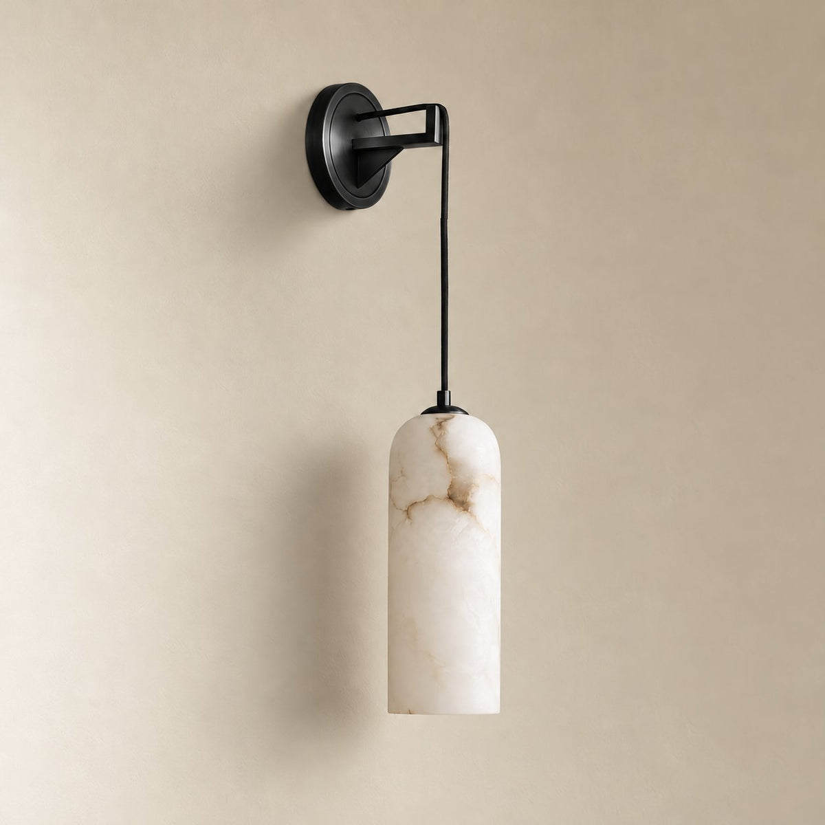 Zêzere round alabaster wall sconce in blackened brass, unlit on a plain plaster wall.