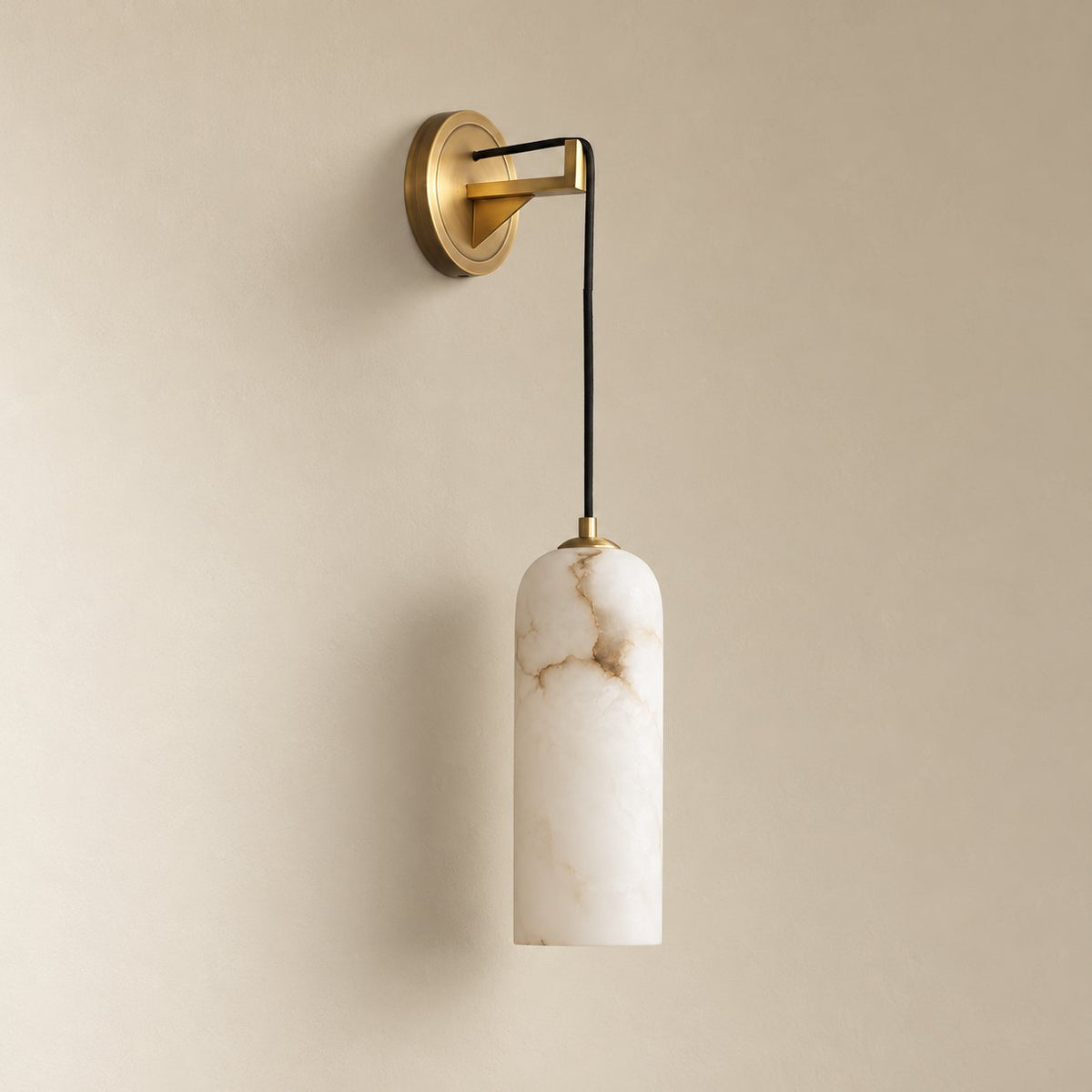 Zêzere round alabaster wall sconce in brass, unlit on a plain plaster wall.